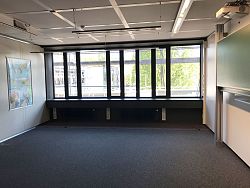 Fensterfront in einem Klassenraum des Scheffel-Gymnasiums von innen fotografiert. Außen sieht man ein Baugerüst. Links an der Wand hängt eine Weltkarte, links eine Schultafel.