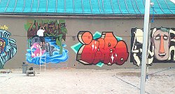 An der &#34;Beachwall&#34; steht ein Graffiti-Künstler auf einer Leiter uns besprüht die Wand mit einem neuen bunten Kunstwerk.