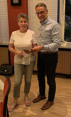 Das Foto zeigt eine Frau und einen Mann, die sich ein Geschenk überreichen.