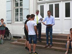 Zu sehen sind Bürgermeister Tilman Petters und Martin Stehr  vom Stadtplanungsamt auf den Stufen des Rathauses bei der Übergabe einer Siegerurkunde an zwei Schüler des Max-Plack-Gymnasiums Lahr.