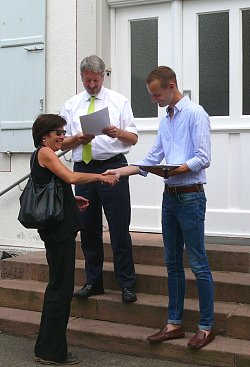 Zu sehen sind Bürgermeister Tilman Petters und Martin Stehr vor dem Rathaus bei der Übergabe einer Siegerurkunde des Stadtradelns 2018 an Carmen Winkler vom Stadtplanungsamt.