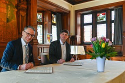 Oberbürgermeister Markus Ibert und Bürgermeister Andrii Naida (von links) unterzeichnen das Memorandum zur Solidarpartnerschaft zwischen Lahr und Kalusch. Sie sitzen im alten Ratssaal vor den Urkunden. 