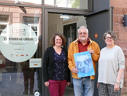 Zu sehen sind Silke Höllmüller (Museumspädagogin), Günter Endres vom Freudeskreis Flüchtlinge Lahr und Gabriele Bohnert (Museumsleiterin)vor dem Eingang des Stadtmuseums. In den Händen hält Günter Endres das blaue Plakat für die Sonderausstellung.