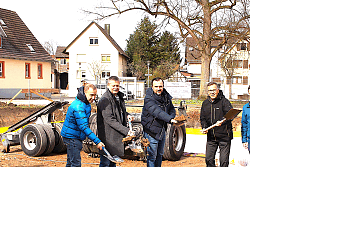 Fünf Menschen beim Spatenstich vor der Baustelle