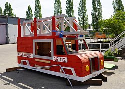 Ein großes Feuerwehrauto aus Holz steht auf dem Hof des Lahrer Bau- und Gartenbetriebs. Es ist rot angemalt. Auf dem Dach ist eine weiße Leiter. Es ist so groß, dass Kinder darin klettern und Spielen können.