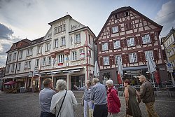 Eine Stadtführerin erklärt einer Personengruppe die verschiedenen historischen Gebäude auf dem Sonnenplatz in Lahr. Im Hintergrund das markante Gebäude "Sonne-Post", das mit seiner bemalten Fassade nach Art der Lüftlmalerei die Blicke auf sich zieht.