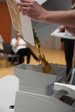 Stadtgulden fallen aus der geöffneten Abstimmungsurne in einen automatischen Münzzähler während der Abstimmung im Oktober 2023