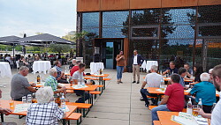 Mietersheims Ortsvorsteherin Diana Frei am Mikrofon, daneben Lahrs Oberbürgermeister Markus Ibert, davor die Gäste auf Bierbänken vor dem Haus am See 