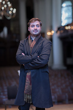 Ein Mann mit braunem Haar und langem Mantel.