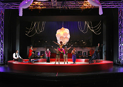 Eine bunte Zirkusbühne vor schwarzem Hintergrund.