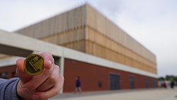 Jemand hält eine Stadt Gulden Lahr Münze in die Kamera, im Hintergrund ist etwas verschwommen die Mehrzweckhalle zu sehen.