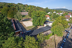 Die große Solarthermie-Anlage auf dem Dach des Terrassenbads sorgt für angenehme Wassertemperaturen und spart damit rund 150 Tonnen CO2 pro Jahr ein. Sie befindet sich auf dem Dach des quadratischen Gebäudes um das Beachvolleyballfelds herum. Im Hintergrund sind die Becken des Terrassenbads.