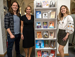 Von links stehen Pirmin Styrnol, Birgit König (Mediathek Lahr) und Anzhelika Kovalenko um ein Bücherregal, das ukrainische Bücher enthält. 