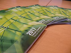 Auf einem Tisch liegen fächerförmig mehrere VHS Programmhefte. Sie sind in verschiedenen Grüntönen gehalten.