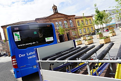 Auf dem Foto ist ein blauer Bus von hinten mit einem Fahrradanhänger zu sehen 
