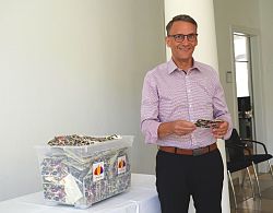 Oberbürgermeister Markus Ibert steht lächelnd neben einer Gewinnspielbox voll von Losen und hält ein Los in der Hand. 