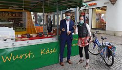 Oberbürgermeister Markus Ibert überreicht einer Marktbesucherin mit Fahrrad ein Willkommensgeschenk.