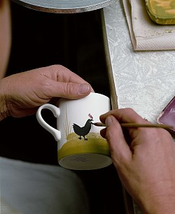 Die Stadt Lahr weist auf interessante Ausflugsziele hin. Hier die Zeller Keramik. Das Bild zeigt die Hand eines Keramikmalers, der das typische Motiv der Zeller Keramik, die Henne, auf eine Tasse malt. 