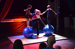 Das Bild zeigt drei junge Artisten, die auf zwei Akrobatikkugeln eine Pyramide bilden.