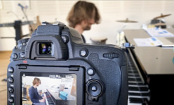 Das Bild zeigt die Rückseite einer Digitalkamera. Das Display zeigt einen Flügel mit einem Pianisten, der Kadenzen für den Youtube-Kanal einspielt. 