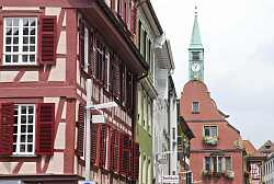 Blick in eine Altstadtstraße mit Fachwerkhäusern und einem Rathaus mit Uhrturm im Hintergrund