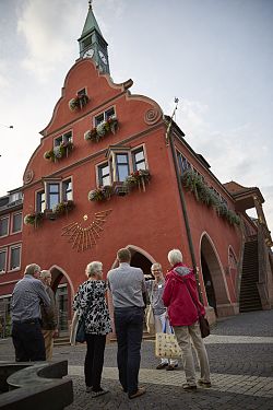 Das Foto zeigt mehrere Menschen bei einer Stadtführung vor einem historischen Gebäude