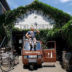 Heiko Feser sitzt auf seiner Ape mit einem Glas Wein