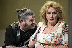 Die blonde Schauspielerin Diana Körner wird in Ihrer Rolle als Paulette von einem Ganoven mit der Pistole bedroht.